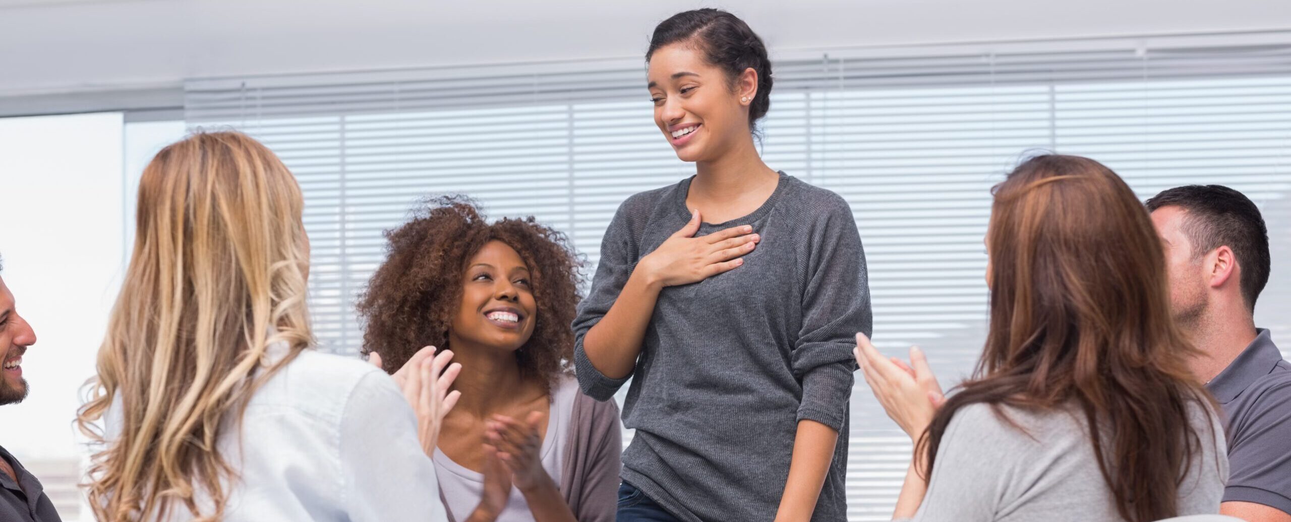 Happy patient has a breakthrough in group therapy while others are clapping her