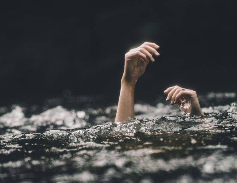 A hand stretches out from the water's surface